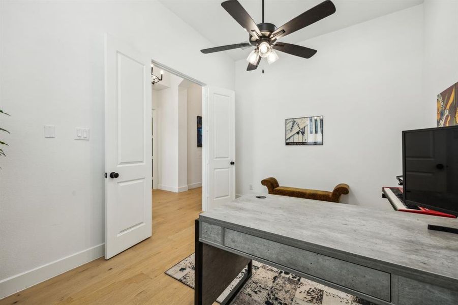 Office area with light wood-type flooring, a ceiling fan, and baseboards