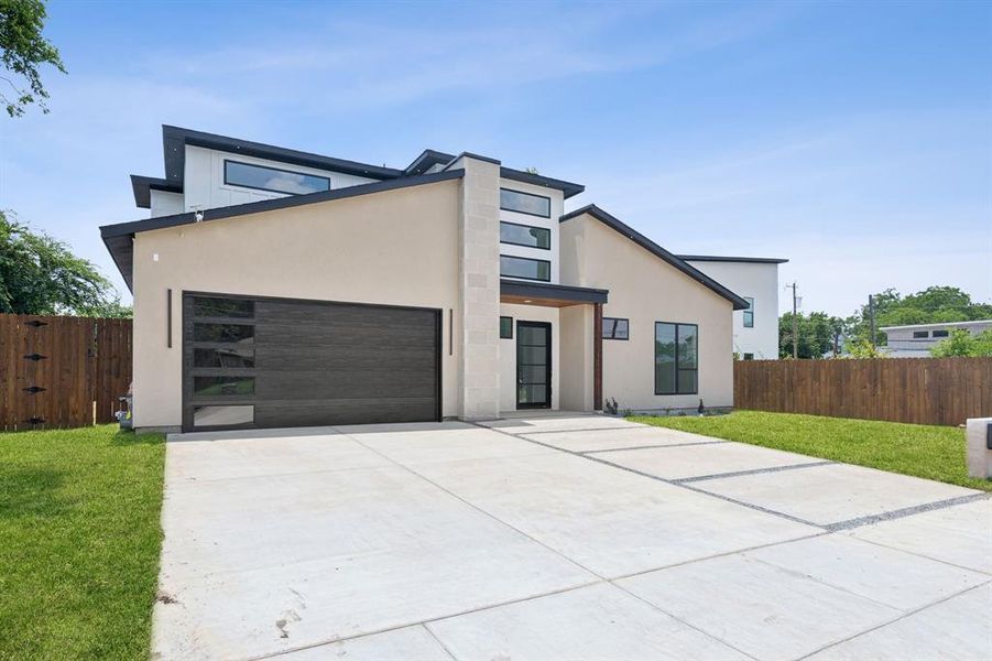 Modern home featuring a garage and a front lawn