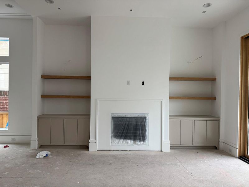 Expansive living room featuring custom white oak shelving and a striking fireplace finished in Venetian plaster, creating a warm yet refined focal point for the space.