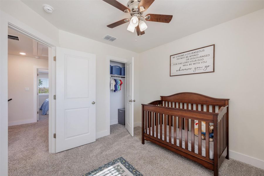 Bedroom with a crib, light colored carpet, a closet, and a ceiling fan Bedroom with a crib, light colored carpet, a closet, and a ceiling fan