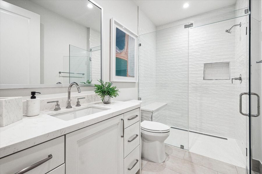 Secondary En-suite guest bathroom with glass framed walk-in shower. Photos are of a similar unit with the same floor plan