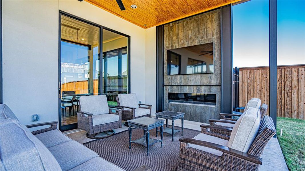 Patio terrace at dusk with an outdoor living space with a fireplace and ceiling fan