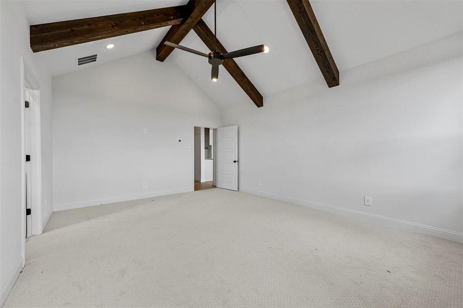 Spare room featuring high vaulted ceiling, beamed ceiling, and carpet