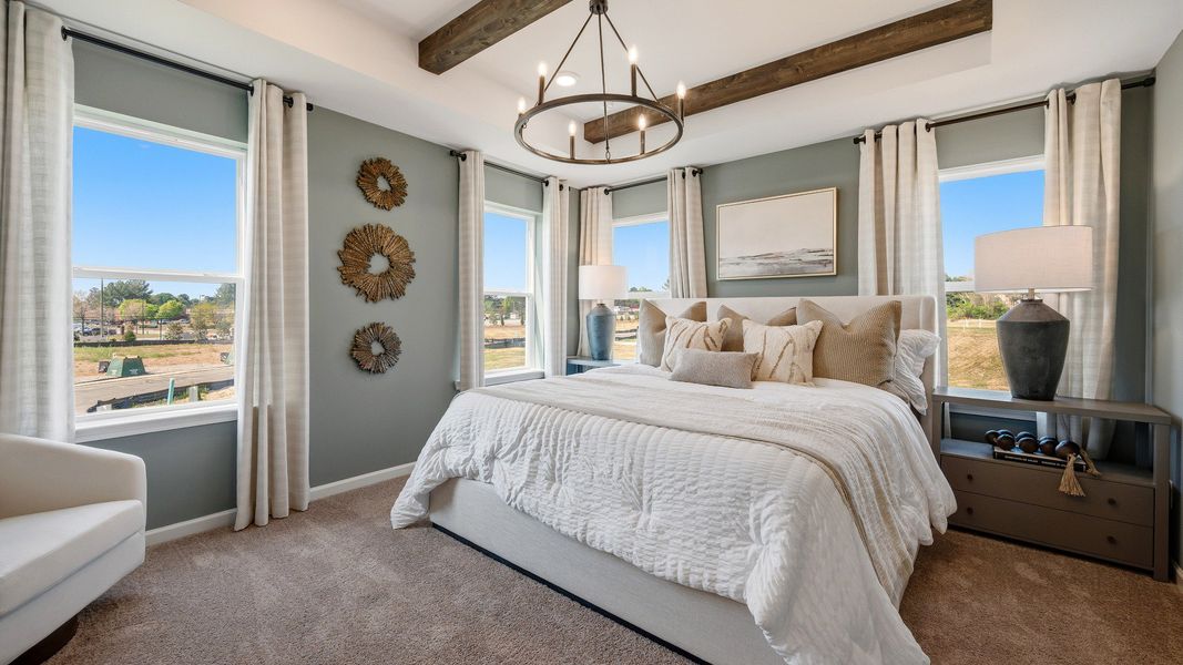 Spacious primary suite with large windows, modern décor, and natural light in Langley Overlook townhome in Loganville, GA.