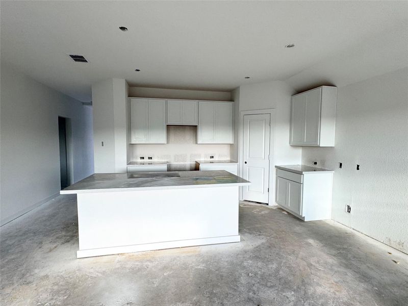 Kitchen featuring white cabinetry, unfinished concrete flooring, a kitchen island, and stovetop