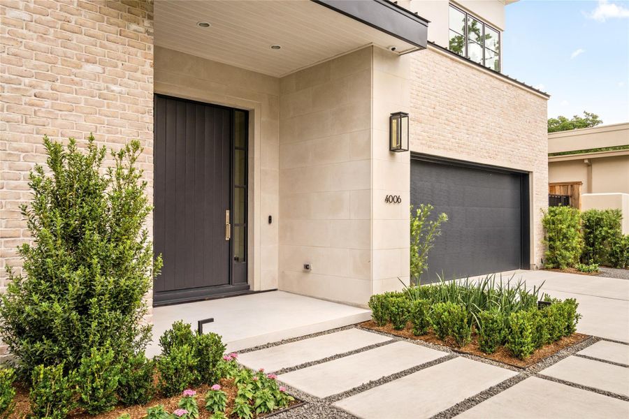 Sleek paver walkways and curated landscaping draw you toward a bold front entry, complemented by a well-integrated three-car garage.