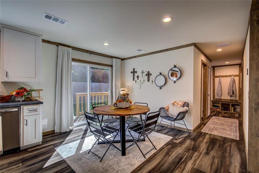 Dining space has sliding glass doors to back deck, and ornamental molding, recessed lighting, and LVP floors