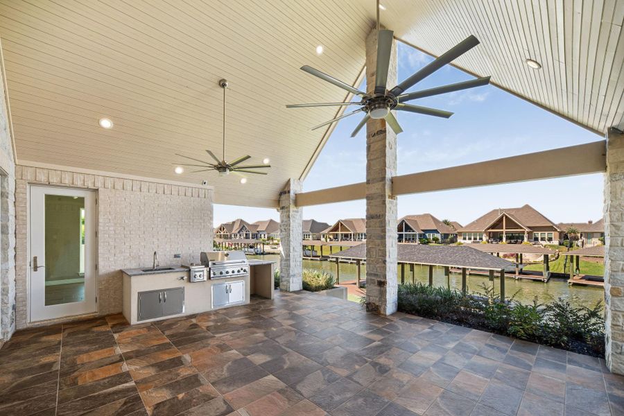 Enjoy year-round entertaining on this spacious covered patio featuring stylish tile flooring, and outdoor kitchen two ceiling fans, and plenty of room for outdoor seating and entertaining.