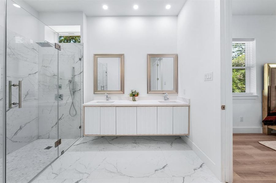 Bathroom with a marble finish shower, double vanity, light marble finish flooring, and recessed lighting Bathroom with a marble finish shower, double vanity, light marble finish flooring, and recessed lighting