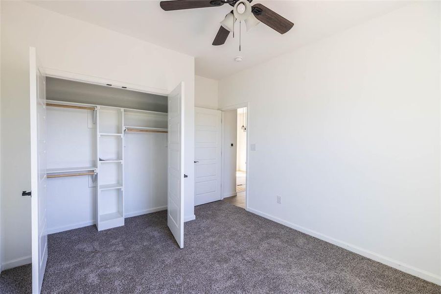 Unfurnished bedroom with dark carpet, a closet, and ceiling fan