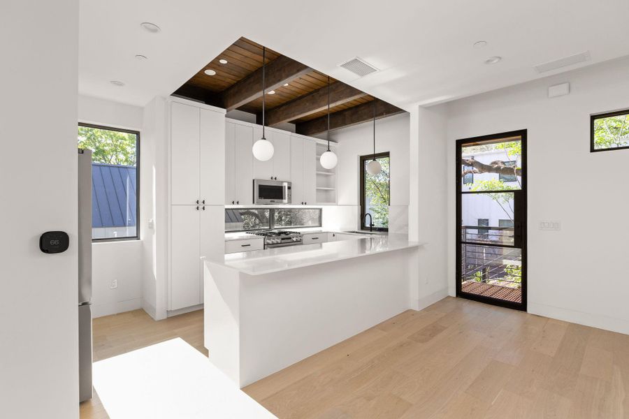 Kitchen with light wood-type flooring, open shelves, a peninsula, pendant lighting, and a wood ceiling with exposed beams