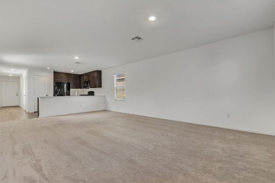 Recessed lighting illuminates this seamless transition from carpeted living space to the adjacent kitchen. Recessed lighting illuminates this seamless transition from carpeted living space to the adjacent kitchen.