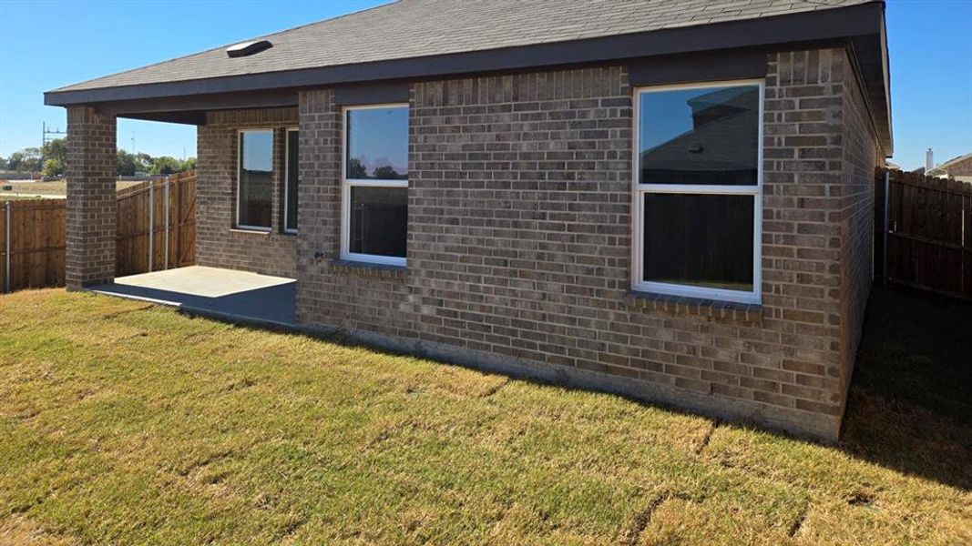 View of home's exterior featuring a fenced backyard, brick siding, a patio area, and roof with shingles View of home's exterior featuring a fenced backyard, brick siding, a patio area, and roof with shingles