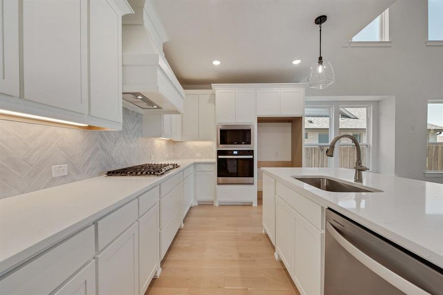 Kitchen with stainless steel appliances, recessed lighting, decorative backsplash, white cabinets, and pendant lighting Kitchen with stainless steel appliances, recessed lighting, decorative backsplash, white cabinets, and pendant lighting