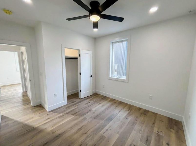Unfurnished bedroom featuring light wood-type flooring, ceiling fan, recessed lighting, and a spacious closet