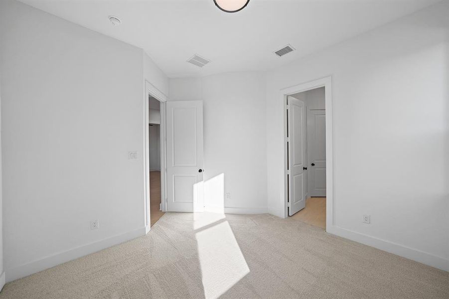 Unfurnished bedroom with light colored carpet and baseboards
