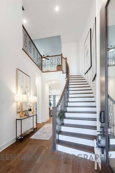 Staircase with wood finished floors, a towering ceiling, and recessed lighting