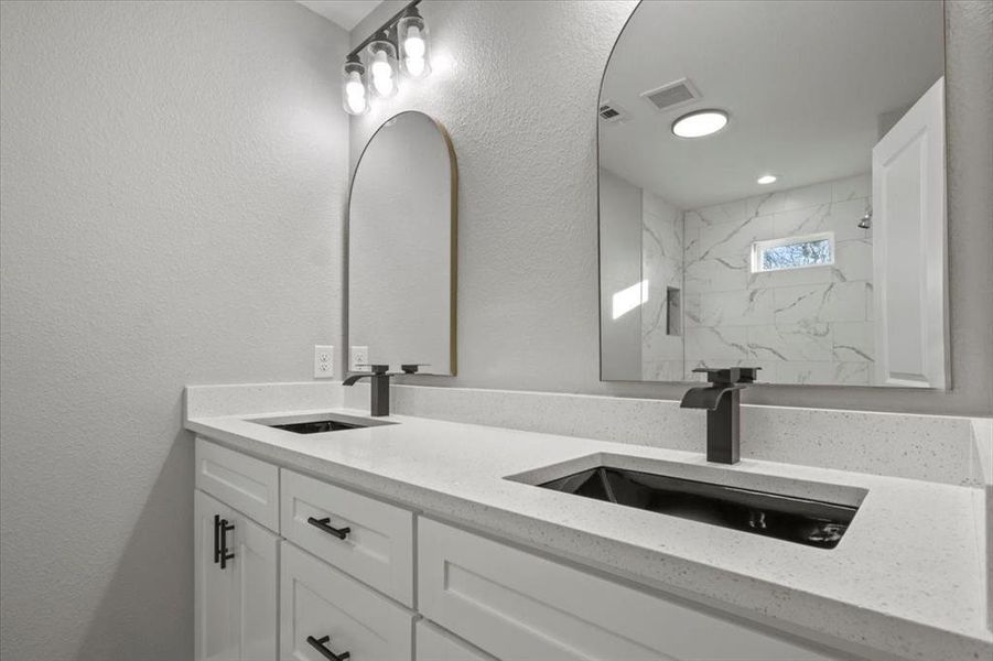 Bathroom featuring tiled shower and vanity