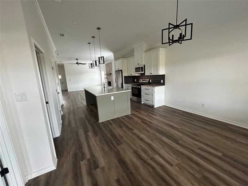 Kitchen with open floor plan, backsplash, pendant lighting, stainless steel appliances, and a chandelier