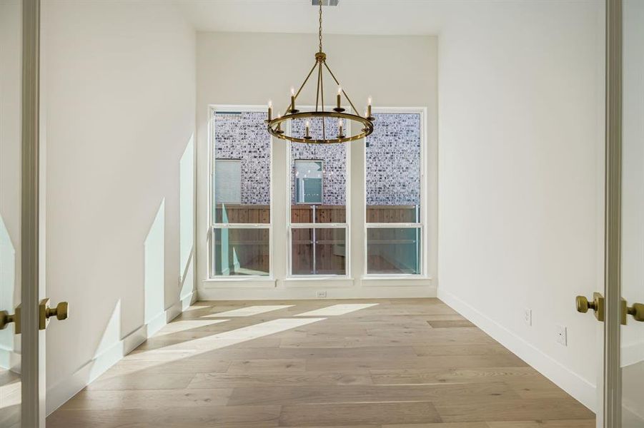 Unfurnished dining area with wood finished floors and a chandelier Unfurnished dining area with wood finished floors and a chandelier