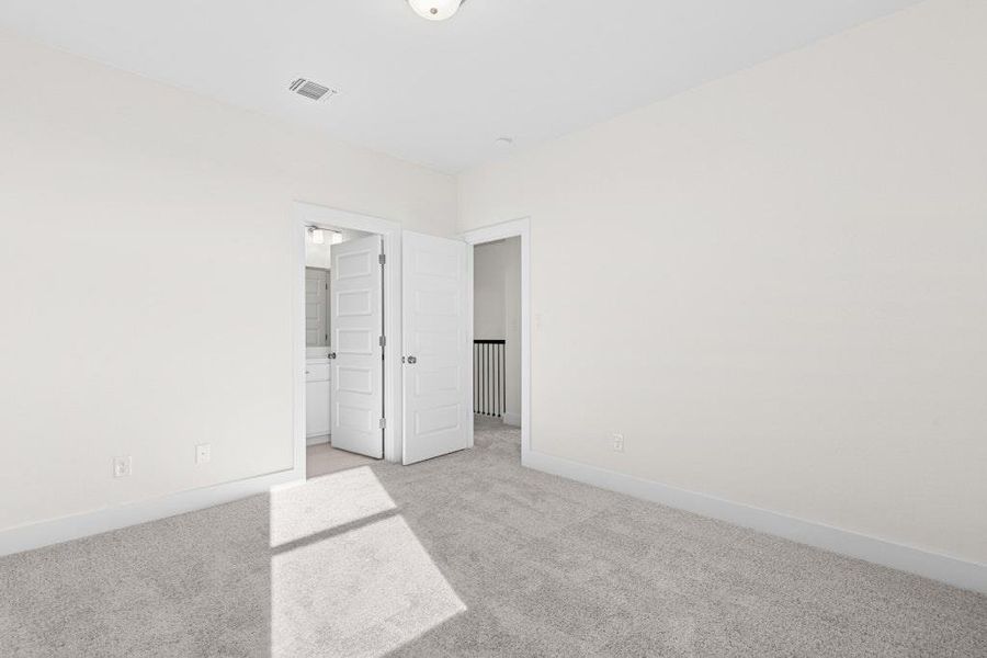 Unfurnished bedroom with light carpet and ensuite bath Unfurnished bedroom with light carpet and ensuite bath