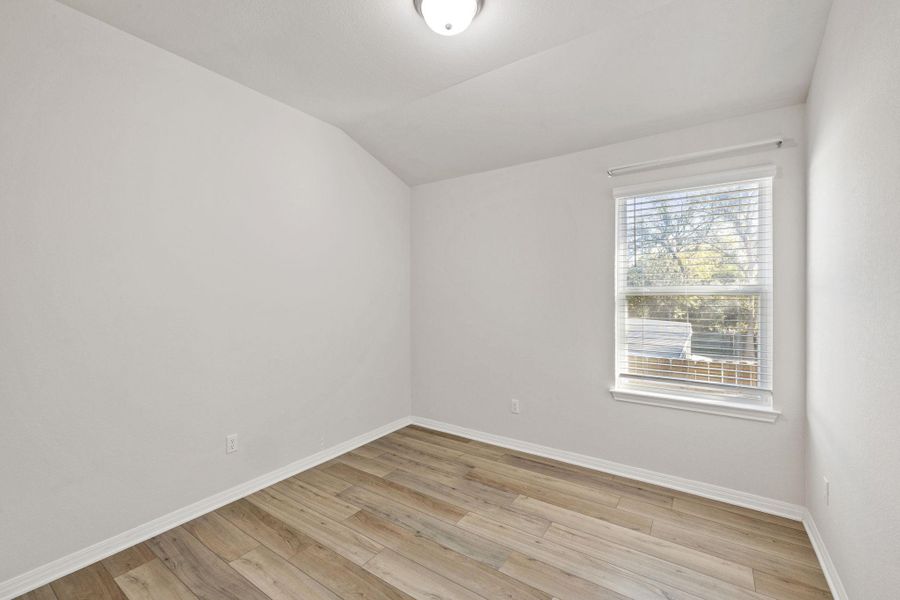 Unfurnished room featuring light wood-style flooring and vaulted ceiling Unfurnished room featuring light wood-style flooring and vaulted ceiling