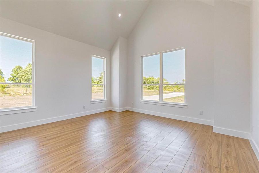 Empty room with high vaulted ceiling and light hardwood / wood-style floors