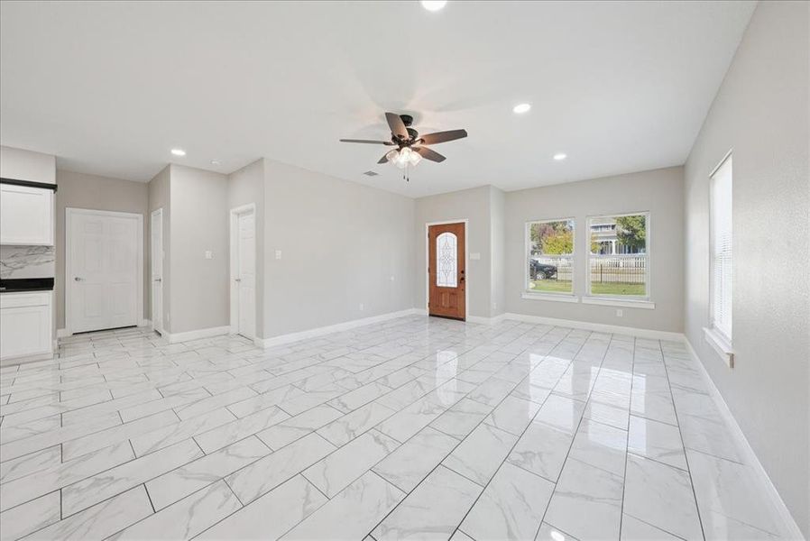 Unfurnished living room featuring light marble finish floors, recessed lighting, and a ceiling fan