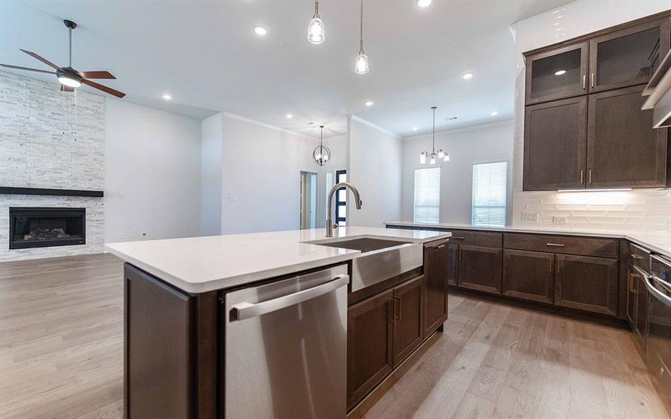 Modern kitchen island featuring a farmhouse sink, stainless steel dishwasher, and light-toned countertop Modern kitchen island featuring a farmhouse sink, stainless steel dishwasher, and light-toned countertop