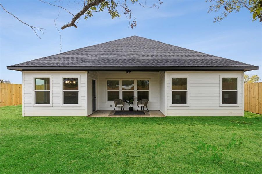 Rear view of house featuring a patio and a lawn