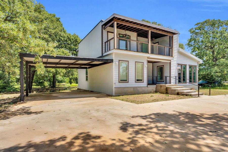 View of front of house with a balcony, concrete driveway, and a carport