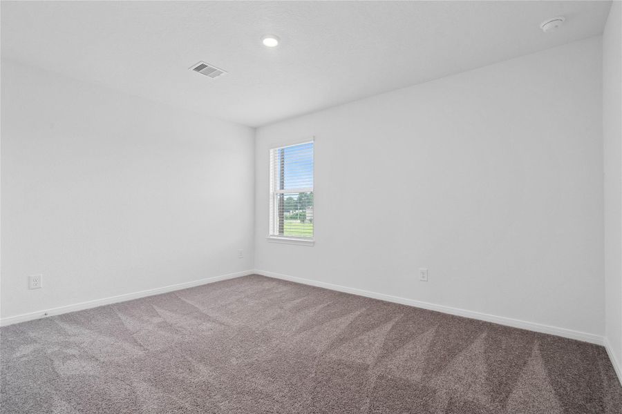 This secondary bedroom offers comfort and style with plush carpeting, neutral paint tones, recessed lighting, a large window, and a generously sized closet. This secondary bedroom offers comfort and style with plush carpeting, neutral paint tones, recessed lighting, a large window, and a generously sized closet.