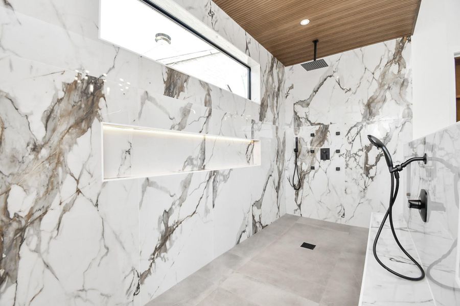 Massive shower with dual shower heads and a sitting area with built in shower head.