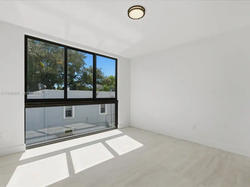 Large multi-panel window with black framing, wood-finish flooring, and flush-mount circular ceiling lighting Large multi-panel window with black framing, wood-finish flooring, and flush-mount circular ceiling lighting