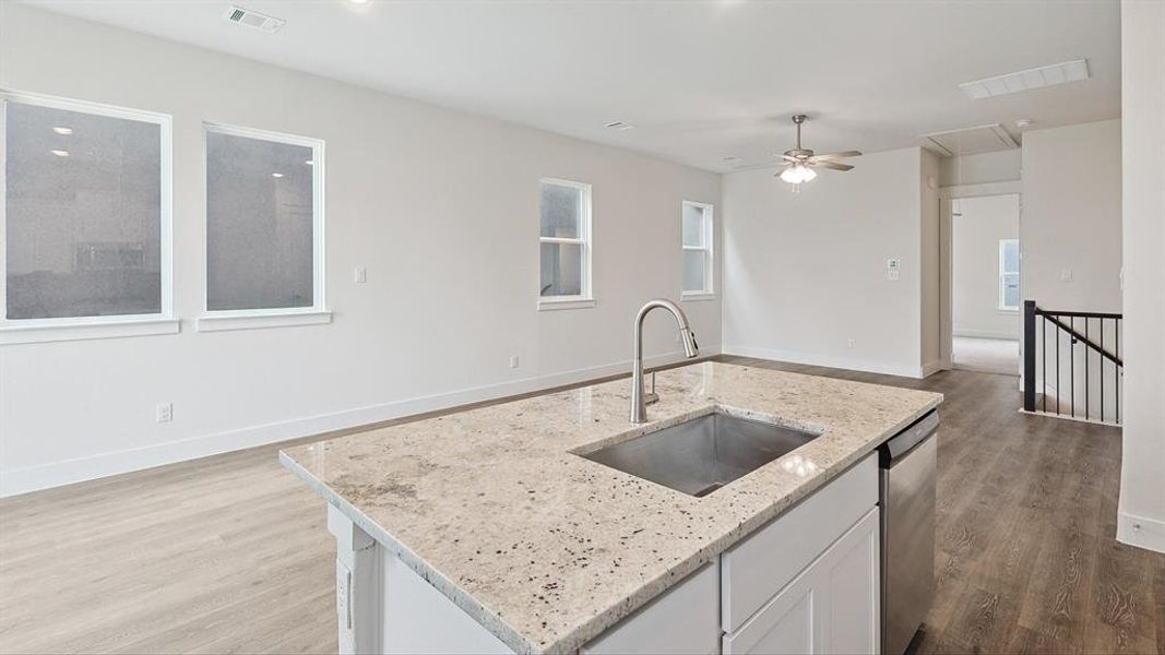 Kitchen island featuring a stainless steel sink, gooseneck faucet, and light-toned granite countertop