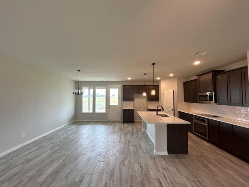Open concept living space featuring wood-finish flooring, a contemporary chandelier, recessed lighting, and a kitchen island with pendant lighting Open concept living space featuring wood-finish flooring, a contemporary chandelier, recessed lighting, and a kitchen island with pendant lighting