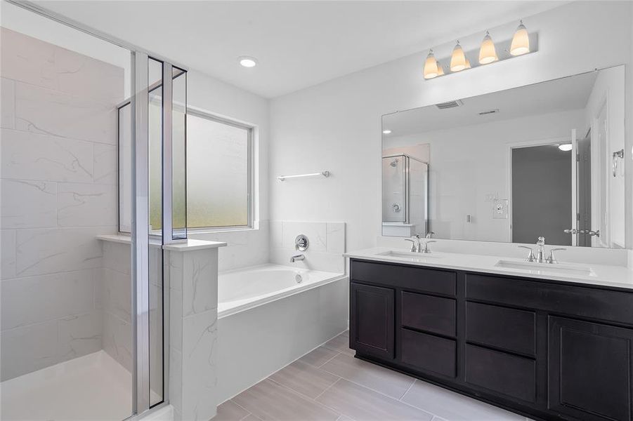 This primary bathroom is definitely move-in ready! Featuring a walk-in shower with tile surround, dark stained cabinets with light countertops, spacious walk-in closet with shelving, high ceilings, custom paint, sleek and dark modern finishes.