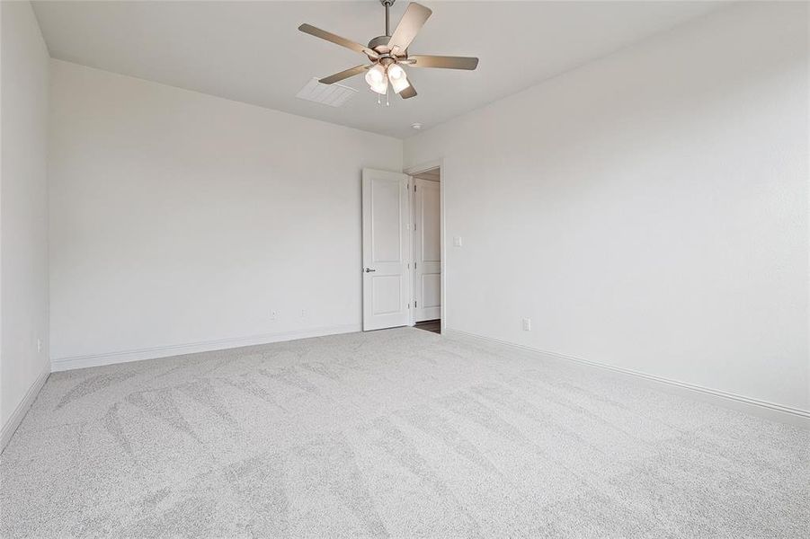 Carpeted empty room featuring ceiling fan