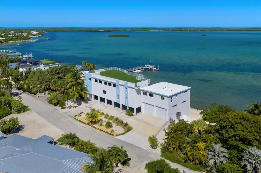 Waterfront property featuring a private dock, expansive rooftop terrace, two-car garage, and established tropical landscaping Waterfront property featuring a private dock, expansive rooftop terrace, two-car garage, and established tropical landscaping