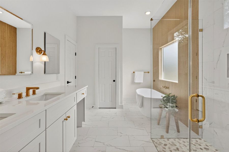 Bathroom featuring a freestanding bath, double vanity, a marble finish shower, light marble finish floors, and recessed lighting