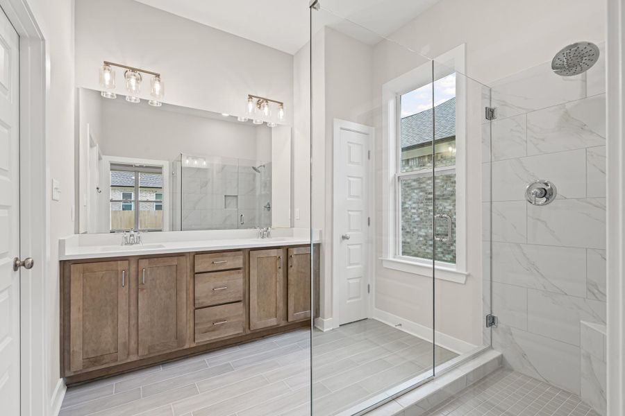 Full bath with a marble finish shower and double vanity