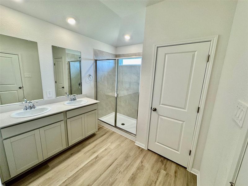 Full bath featuring a stall shower, wood finished floors, double vanity, and recessed lighting Full bath featuring a stall shower, wood finished floors, double vanity, and recessed lighting