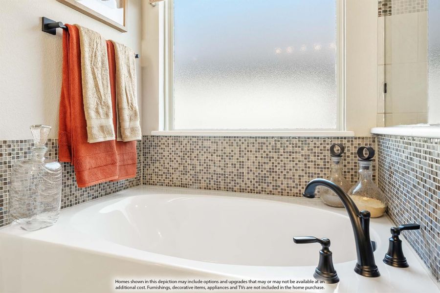 Soaking tub with dark bronze faucet, mosaic tile surround, and frosted privacy window above Soaking tub with dark bronze faucet, mosaic tile surround, and frosted privacy window above