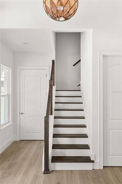 Staircase detail showcasing the dark wood treads and white risers, leading to the upper level of the home, adjacent to the foyer and a nearby door.