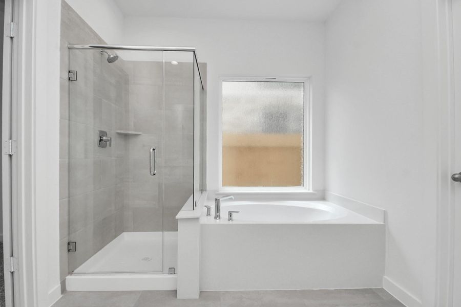 Indulge in a spa-like retreat within the confines of this primary bathroom. Delight in a spacious walk-in shower enveloped in stylish tile surround, unwind in a separate garden tub adorned with custom detailing. Sample photo of completed home with similar floor plan. Actual colors and selections may vary. Indulge in a spa-like retreat within the confines of this primary bathroom. Delight in a spacious walk-in shower enveloped in stylish tile surround, unwind in a separate garden tub adorned with custom detailing. Sample photo of completed home with similar floor plan. Actual colors and selections may vary.