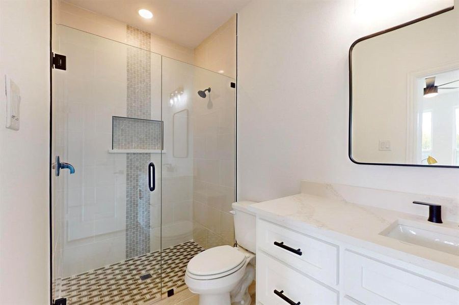 Bathroom with ceiling fan, a shower with door, vanity, and toilet