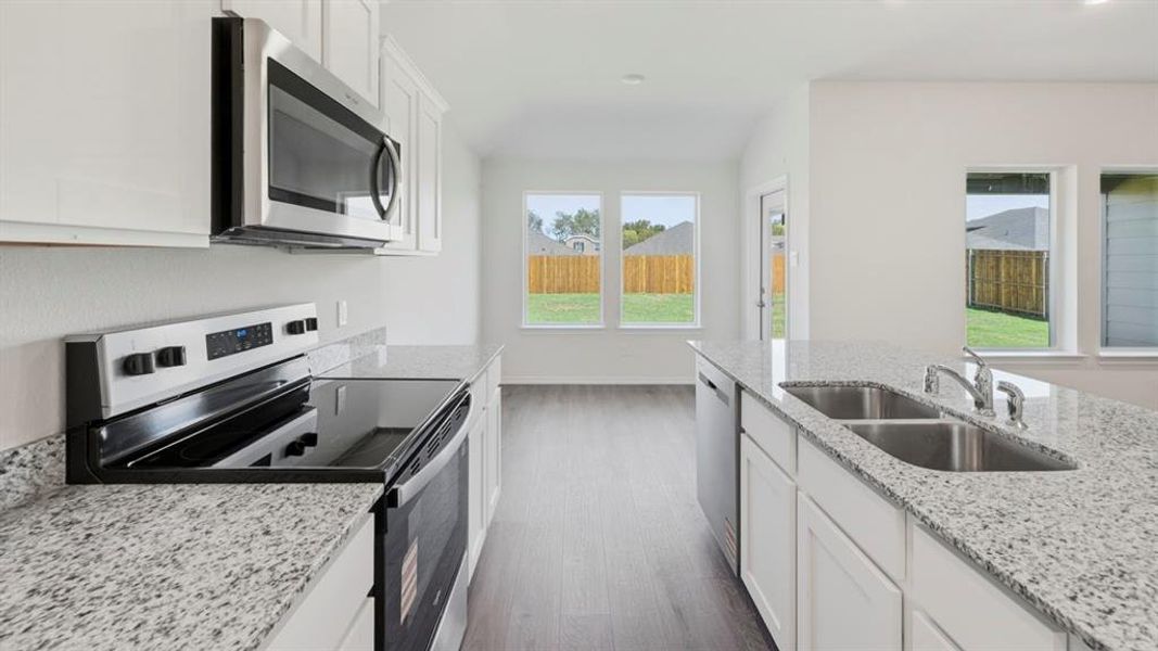 Kitchen featuring stainless steel appliances, white cabinetry, light stone countertops, and dark wood-style flooring Kitchen featuring stainless steel appliances, white cabinetry, light stone countertops, and dark wood-style flooring