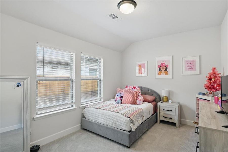 Bedroom with vaulted ceiling, light colored carpet, visible vents, and baseboards