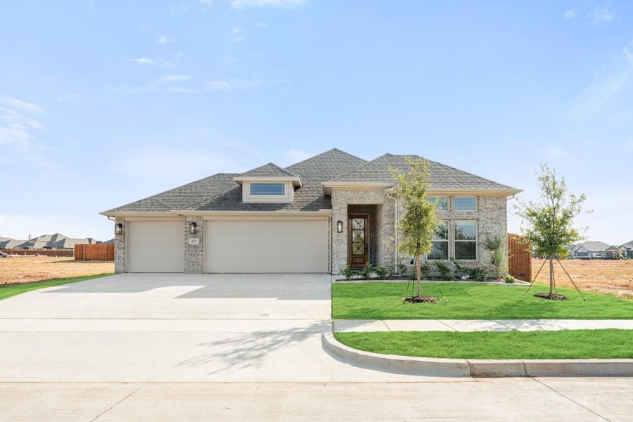 Single-story brick home with two-car garage, wood front door, and freshly landscaped lawn