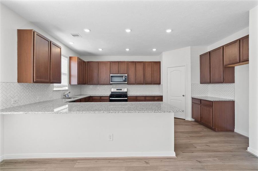 This kitchen will not disappoint! Your family and guests will enjoy many nights of fun, food and entertainment with ample counter space and kitchen island for setting up a wonderful array of provisions! This view of this gorgeous kitchen showcases SS appliances, granite countertops, beautiful tile backsplash, gas range, high ceiling, recessed lighting and tile floors!